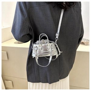 Detail of silver crocodile pattern mini bag featuring a drawstring closure and metal strap