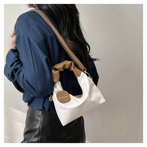 Dettaglio borsa hobo bianca con manico marrone a pieghe e ciondolo logo sul modello