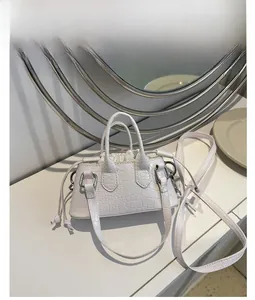 Detail of white faux leather crossbody bag with crocodile texture and drawstring lining