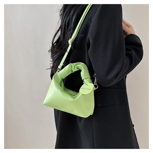 Dettaglio della borsa tote verde neon con pieghe, ciondolo tondo e tracolla regolabile
