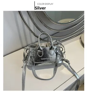 Detail shot of silver mini crossbody bag showing crocodile texture and drawstring lining