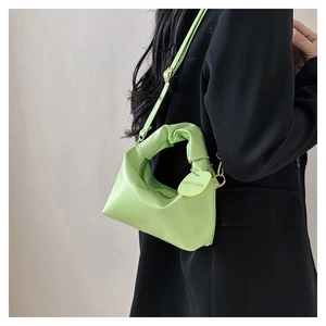 Dettaglio borsa verde neon con manico increspato e cartellino moda su abito nero