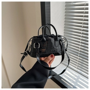 Detail of black faux crocodile leather mini bag with embossed fashion text and drawstring