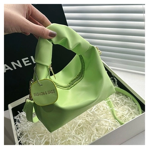 Dettaglio della borsa a mano verde chiaro con tracolla regolabile in scatola bianca