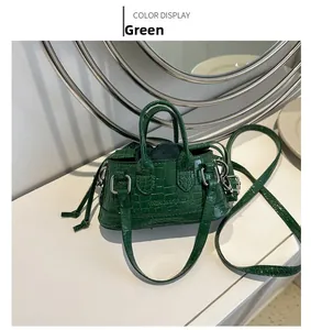 Detailed view of a green mini tote bag featuring crocodile embossing and fashion text