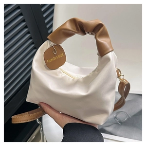 Dettaglio della borsa tote color crema con manici plissettati e ciondolo logo