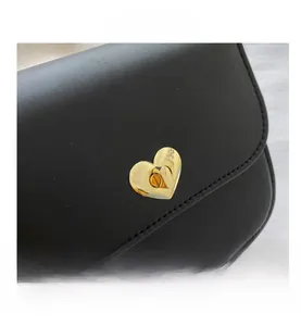 Gros plan du sac bandoulière noir avec fermoir rotatif métallique en forme de cœur doré