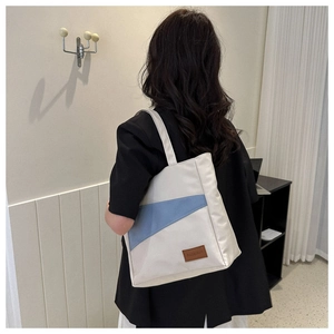 Detail view of canvas tote bag with geometric blue contrast and brown leather fashion tag