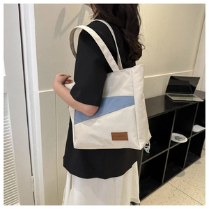 Detail of canvas tote bag showing Morandi blue diagonal patchwork and leather fashion tag