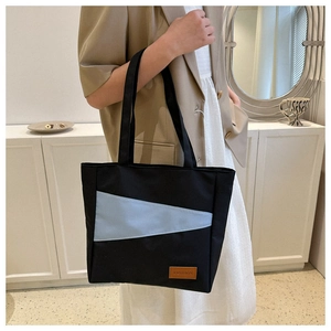 Detail of black oxford tote bag with blue stripes and a leather fashion tag