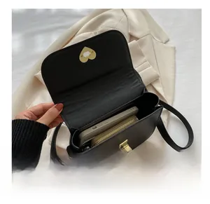 Détail de l'intérieur du sac à bandoulière noir contenant un téléphone et un portefeuille