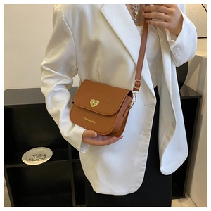 Gros plan d'un sac bandoulière vintage marron avec boucle cœur dorée et logo chic