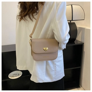 Détail d'un sac à bandoulière beige avec fermoir rotatif doré en forme de cœur