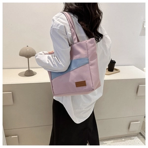 Detail of pink and blue canvas tote bag with fashion leather patch on model shoulder
