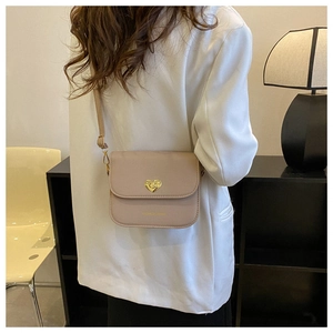 Détail du petit sac rose avec fermoir rotatif en forme de cœur doré sur cuir mat