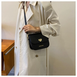 Détail du sac bandoulière noir mat avec fermoir cœur doré et lettrage du logo