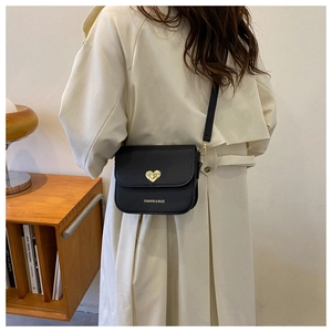 Détail du petit sac noir avec fermoir cœur doré et inscription de mode gravée