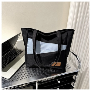 Detail of black and blue Oxford tote bag with leather Fashion tag on a shelf