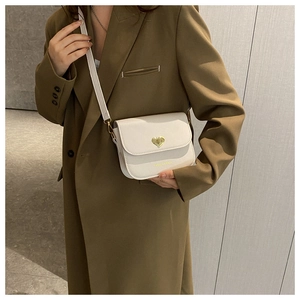 Détail du sac bandoulière en cuir blanc avec fermoir métallique doré en forme de cœur
