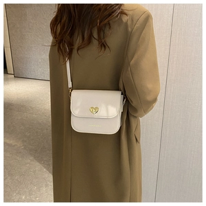 Détail du sac à bandoulière crème avec fermoir coeur doré et logo imprimé chic