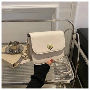 Détail d'un sac bandoulière crème avec fermoir coeur doré et texture en cuir PU