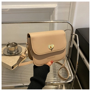 Gros plan détaillé d'un sac bandoulière beige avec fermoir rotatif cœur doré
