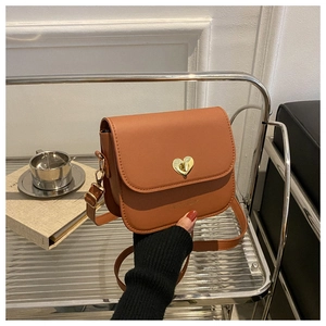 Détail d'un sac bandoulière en cuir marron avec fermoir rotatif doré en forme de cœur