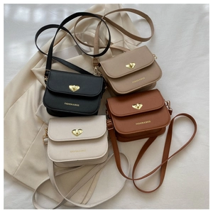 Détail de quatre sacs à bandoulière en cuir mat noir, kaki, marron et blanc avec fermoirs cœur