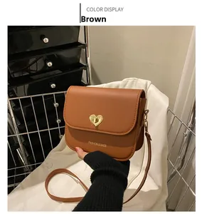 Détail du sac bandoulière en cuir PU marron avec verrou coeur doré et texte de mode