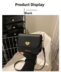 Détail du sac bandoulière en cuir noir avec un fermoir tournant en métal doré en cœur