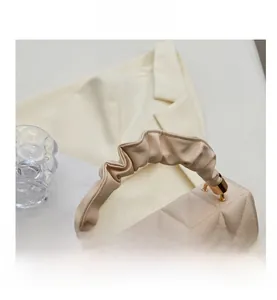 Détail du sac à main matelassé beige avec anse froncée et finitions dorées élégantes