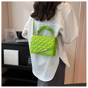 Détail du sac bandoulière vert avec matelassage géométrique et poignée à volants