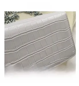 Detail shot of light purple crocodile embossed leather handbag with silver chain