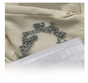 Close-up of white crocodile texture faux leather with silver metal chain strap detail