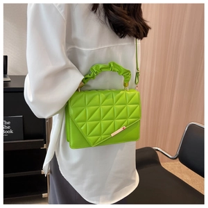 Gros plan d'un sac matelassé vert néon avec poignée froncée et boucle métallique élégante