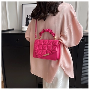 Détail du sac bandoulière matelassé magenta avec poignée plissée et bordure métallique