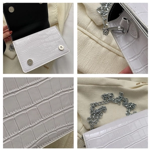 Macro detail of white crocodile pattern leather bag with silver magnetic snap buckle