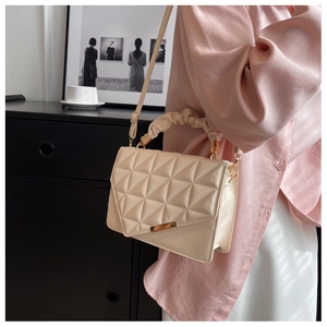 Détail d'un sac bandoulière beige matelassé avec poignée nuage et garniture dorée