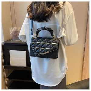 Détail du sac à main en cuir matelassé noir avec barre dorée et poignée plissée