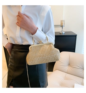 Detail of beige straw woven crossbody bag with vintage gold metal frame and ball clasp