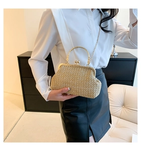 Detail of raffia straw cloud bag featuring gold metal handle and chain shoulder strap