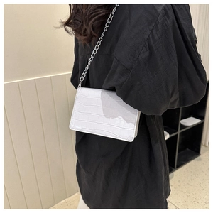 Detail of white crocodile pattern leather handbag with elegant silver chain strap