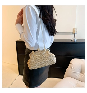 Detail of vintage straw woven clutch bag with gold metallic frame and chain strap