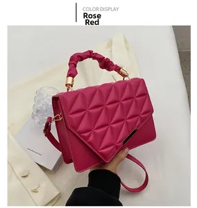 Détail d'un sac à main matelassé rose rouge avec poignée plissée et fermoir tournant doré