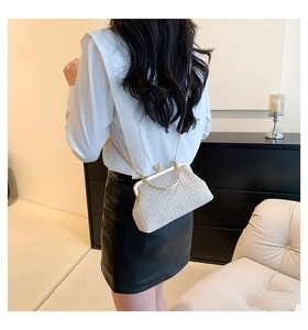 Straw woven crossbody bag shown worn at waist with elegant gold chain strap and ring handle