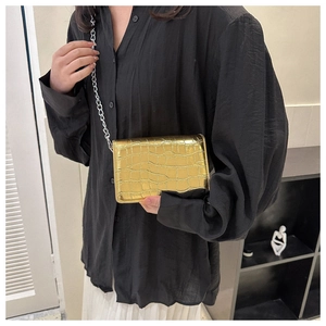 Detail of gold croc-embossed mini square bag with elegant silver chain strap for women