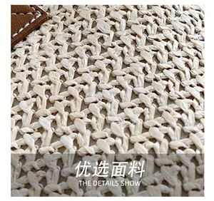 Close-up of cream woven fabric with brown leather trim and white stitching detail