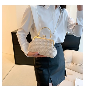 Close-up of woven straw handbag with gold metal clasp and hollow pattern handle