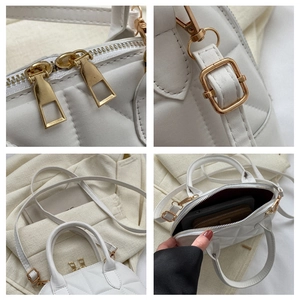 Detailed view of white quilted handbag with golden zippers and metal hardware