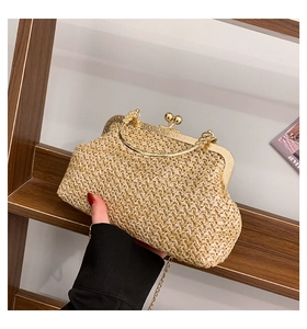 Detail of vintage straw woven bag with gold engraved metal kiss lock and chain strap